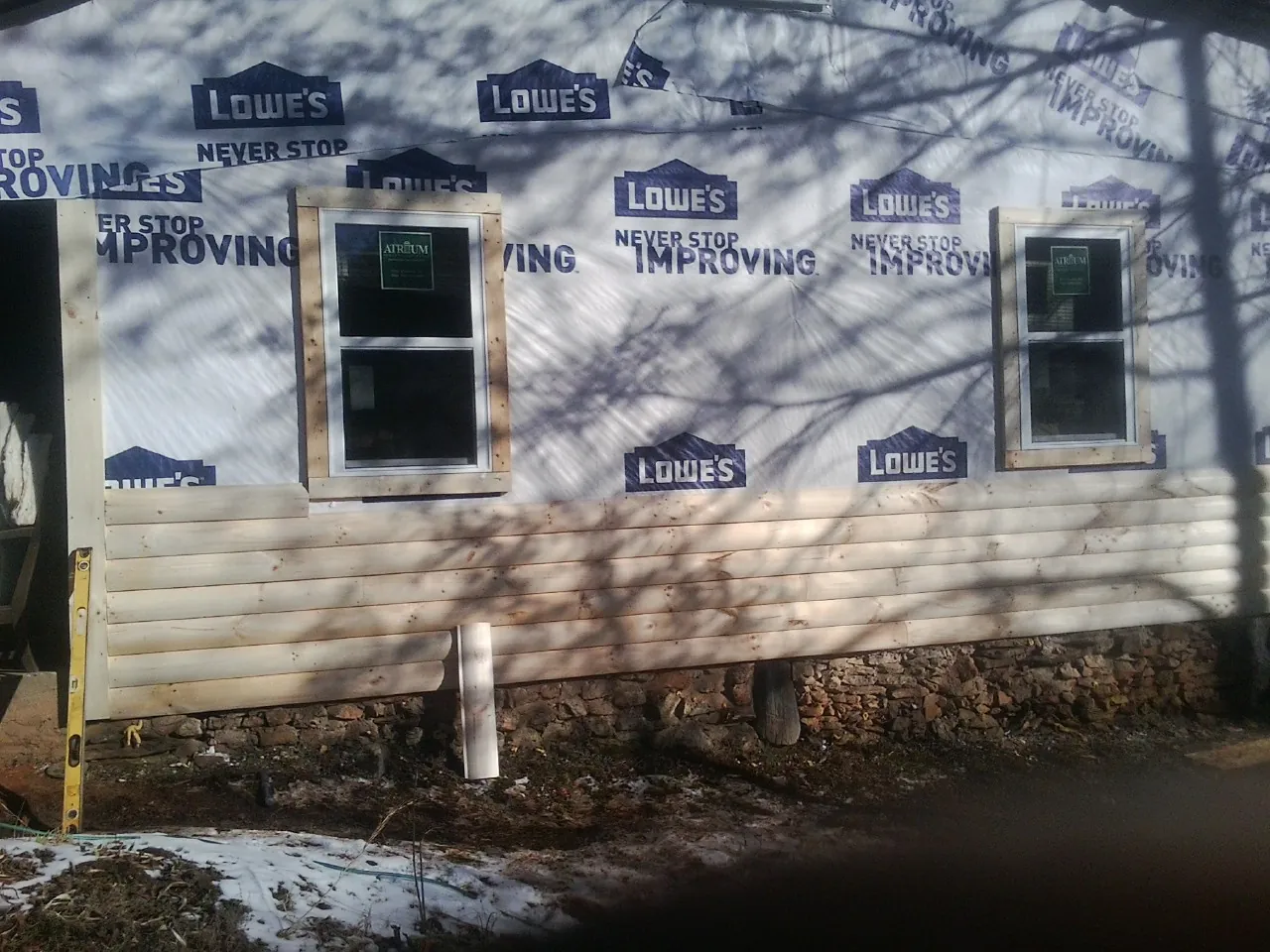 House wrap and new log siding going up on an exterior wall in Benedict