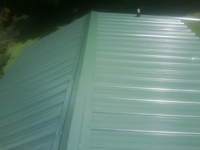 New green metal panels meeting at the ridge of a roof — Flat Roof Repair work by our crew in Benedict