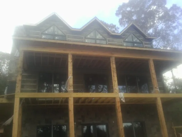 Dormers and porch framing on a large log home under construction — Roof Coating work by our crew in Benedict