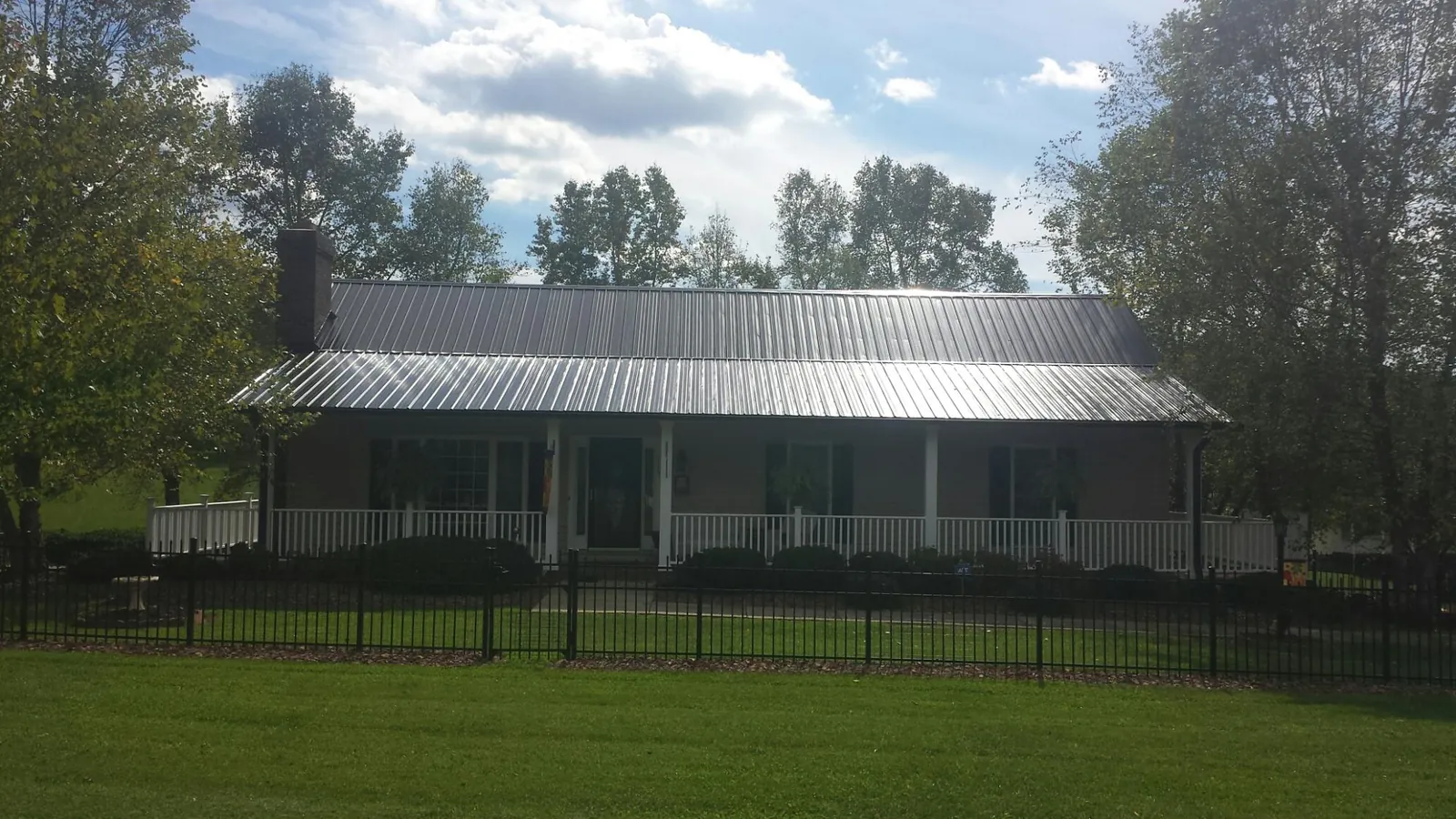 Gray metal roof on a brick ranch with a full width front porch — Gutter Guard Installation work by our crew in Benedict